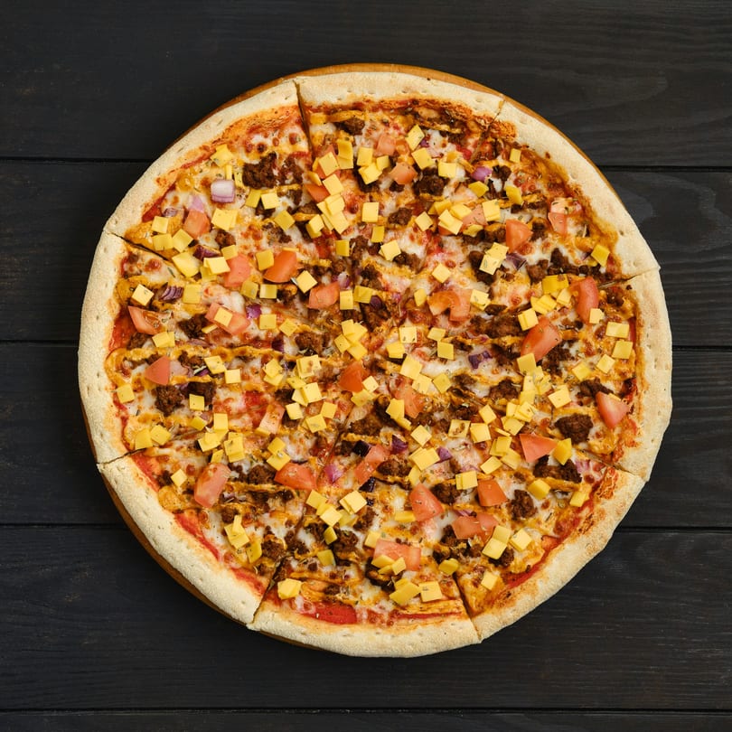 Twisted Pizza's sliced pizza with ground meat, diced tomatoes, red onions, and cheese cubes.
