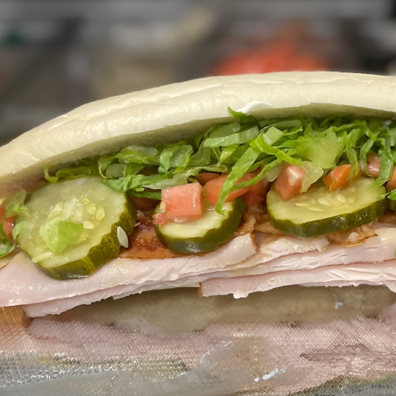 A Twisted Pizza sub sandwich filled with turkey, lettuce, tomatoes, and pickles.